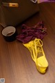 A pair of yellow shoes and a purple bra on a wooden floor.