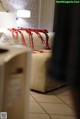 A bed with a white headboard and a red blanket on it.