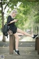 A woman sitting on top of a wooden post looking at her phone.