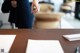 A woman standing at a table with a pen and paper.