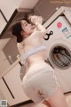 A woman standing in front of a washing machine in a kitchen.