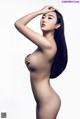 A naked woman with long black hair posing for a picture.