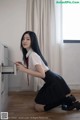 A woman in a school uniform is sitting on the floor.