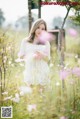 A woman in a white dress standing in a field of flowers.