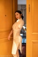 A woman in a white dress standing in front of a door.