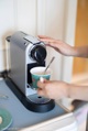 A person is pouring a cup of coffee into a coffee machine.