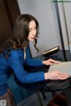 A woman in a blue dress sitting at a desk.