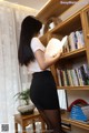 A woman in a white shirt and black skirt is reading a book.