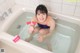 A woman sitting in a bathtub holding a toothbrush.