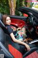 A woman sitting in the driver's seat of a red sports car.