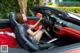 A woman sitting in the driver's seat of a red sports car.