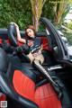 A woman sitting in the back seat of a red and black car.