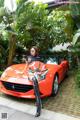 A woman sitting on top of a red sports car.