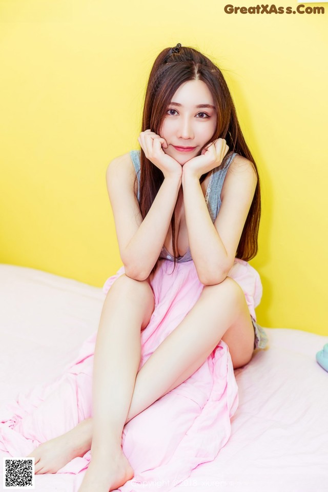A woman sitting on top of a bed with her legs crossed.
