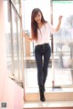 A woman standing in front of a glass door.