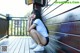 A woman sitting on a wooden deck with her legs crossed.