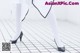 A woman in white tights and black shoes standing on a tiled floor.