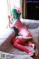 A woman in a pink nurse outfit sitting on a bed.