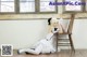 A woman in a white dress sitting on a wooden chair.