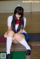 A woman in a school uniform sitting on the floor.