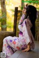 A woman in a kimono sitting on a wooden bench.