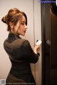 A woman in a black shirt is opening an elevator door.