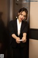 A woman in a business suit standing in an elevator.