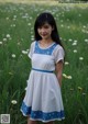 A woman standing in a field of daisies wearing a white dress.