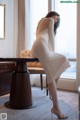 A woman in a white dress sitting at a table.