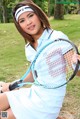 A woman in a blue dress holding a tennis racket and ball.