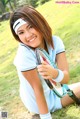 A woman sitting on the grass holding a tennis racket.