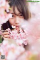 A young woman holding a branch of a tree with pink flowers.