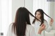 A woman brushing her hair in front of a mirror.