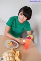 A woman sitting at a table with a plate of food and a drink.