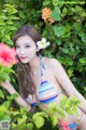 A woman in a bikini posing in front of flowers.