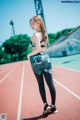 A woman standing on a running track with her back to the camera.