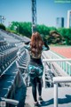 A woman standing on a stadium with her back to the camera.