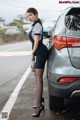 A woman standing next to a car in a parking lot.