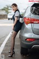 A woman standing next to a car in a parking lot.