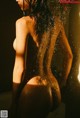 A naked woman standing in a shower with water splashing on her body.