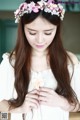 A woman with long brown hair wearing a flower crown.