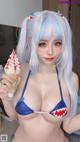 A woman in a blue bikini holding an ice cream cone.