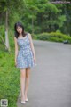 A woman in a blue dress standing on a road.