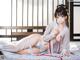 A woman in a white kimono laying on a bed.