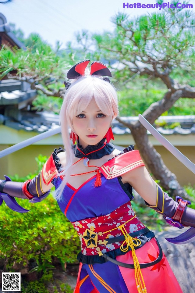 A woman dressed in a red and blue outfit holding two swords.