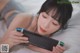 A woman laying on a bed holding a Nintendo Switch.