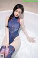 A woman in a blue and red bodysuit sitting in a bathtub.