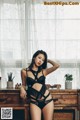 A woman in a black lingerie posing in front of a window.