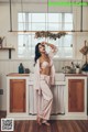 A woman in a pink robe standing in a kitchen.