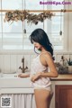 A woman standing in a kitchen next to a sink.